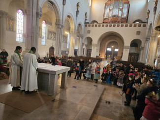 Köigskinder mit gebastelten Kronen stehen um den Altar